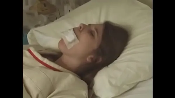 Mostrar linda morena de camisa de com fita adesiva na boca amarrada a cama do hospital Clipes de unidade